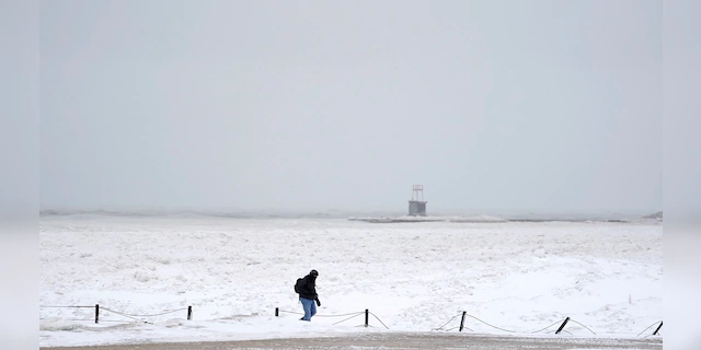 A lone man walks along a frozen section of North Ave. beach on Lake Michigan north of downtown Chicago on Tuesday. (AP)