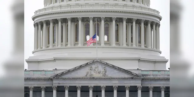 An American flag flies at half-staff in remembrance of U.S. Capitol Police Officer Brian Sicknick above the Capitol Building in Washington on Friday. A Pennsylvania teacher has been put on leave pending an investigation into his involvement in the protest before the riot in the Capitol. (AP Photo/Patrick Semansky)