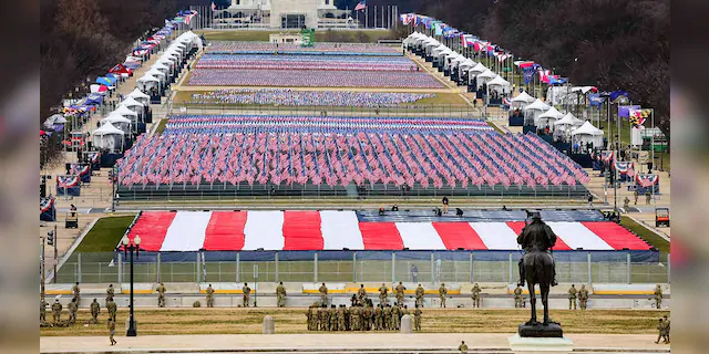 Members of the National Guard look on as American flags decorate the "Field of Flags" at the National Mall ahead of President-elect Joe Biden's inauguration ceremony, Wednesday, Jan. 20, 2021, in Washington. (Tasos Katopodis/Pool Photo via AP)