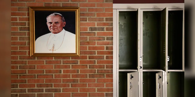 A portrait of St. John Paul II hangs beside a row of empty lockers in the main hallway of Quigley Catholic High School in Baden, Pa., in June 2020. (AP)