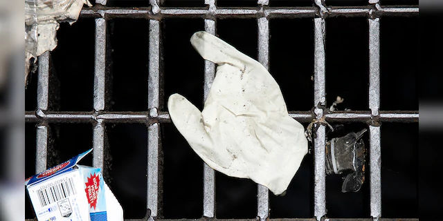 This Monday, May 25, 2020 photo shows a discarded glove on a storm drain in Philadelphia. (AP Photo/Matt Rourke)