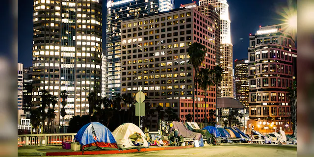  Homeless tents are pictured near the highway in LA Downtown with skyscrapers. (iStock)