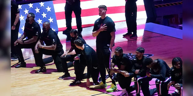 The Miami Heat team kneels during the playing of the national anthem before the first half of an NBA basketball game against the Miami Heat, Wednesday, Jan. 6, 2021, in Miami. (AP Photo/Marta Lavandier)