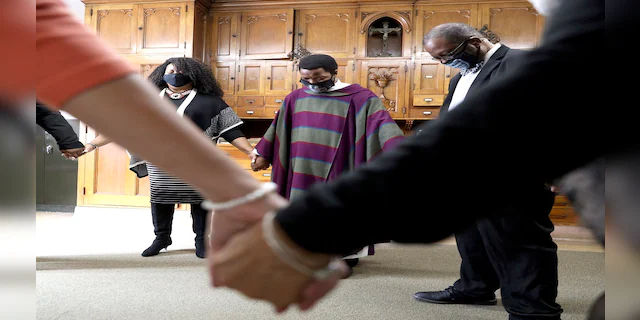 Pastor Thulani Magwaza, center, prays with staff members in the backroom before a Sunday church service at St. Sabina Catholic Church in the Auburn Gresham neighborhood in Chicago, on March 7. (AP)