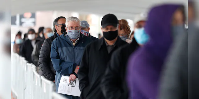 People wait in line at the check-in area to enter the United Center mass COVID-19 vaccination site Wednesday, March 10, 2021, in Chicago. 