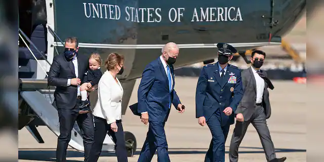 President Joe Biden, center, walks from Marine One to board Air Force One, with son Hunter Biden, left, as he carries his son Beau, Friday, March 26, 2021, at Andrews Air Force Base. (AP Photo/Alex Brandon)