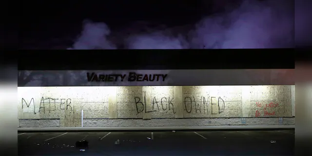 A business labeled "Black Owned" remains untouched by looters, Friday, May 29, 2020, in Minneapolis. Protests continued following the death of George Floyd, who died after being restrained by Minneapolis police officers on Memorial Day. (AP Photo/John Minchillo)