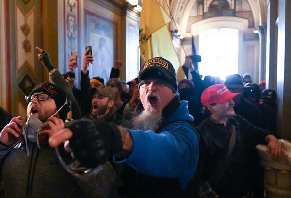 Jon Ryan Schaffer wearing a blue jacket and a hat that reads “Oath Keepers, Lifetime Member” while inside the Capitol on Jan 6.