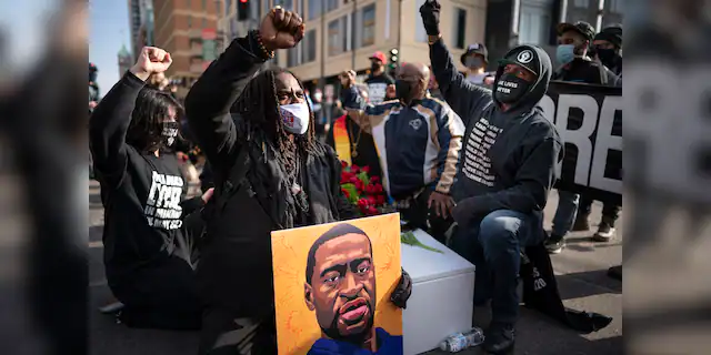 Cortez Rice, left, of Minneapolis, sits with others in the middle of Hennepin Avenue on Sunday, March 7, 2021, in Minneapolis, Minn., to mourn the death of George Floyd a day before jury selection is set to begin in the trial of former Minneapolis officer Derek Chauvin, who is charged in Floyd's death. (Jerry Holt/Star Tribune via AP, File)