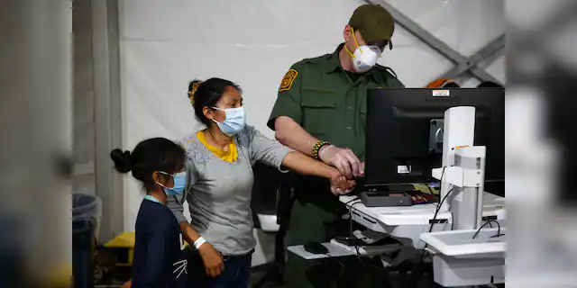 In this March 30, 2021, file photo, a migrant and her daughter have their biometric data entered at the intake area of the U.S. Department of Homeland Security holding facility, the main detention center for unaccompanied children in the Rio Grande Valley, in Donna, Texas. (AP Photo/Dario Lopez-Mills, Pool, File)
