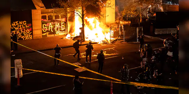 Protesters watch a structure fire, set following the police shooting of a homeless man on April 17, 2021 in Portland, Oregon. (Photo by Nathan Howard/Getty Images)