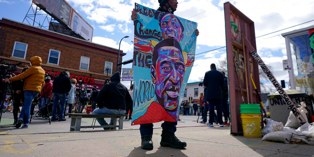 A man holds a sign at George Floyd Square, Wednesday, April 21, 2021, in Minneapolis, a day after former Minneapolis police Officer Derek Chauvin was convicted on all counts for the 2020 death of Floyd.