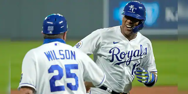 In this Thursday, Sept. 24, 2020 photo, Kansas City Royals' Salvador Perez celebrates with third base coach Vance Wilson after hitting a three-run home run during the first inning of the team's baseball game against the Detroit Tigers in Kansas City, Mo. (AP Photo/Charlie Riedel, File)