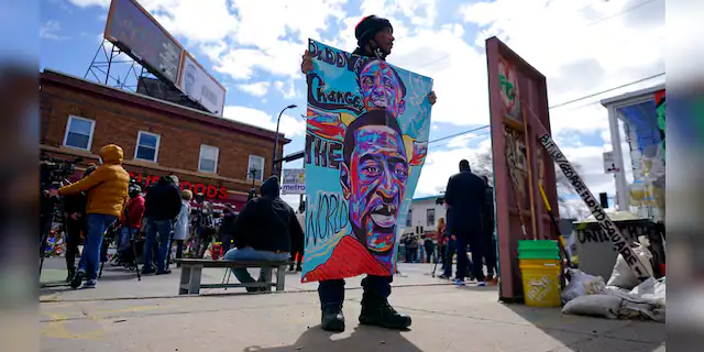 A man holds a sign at George Floyd Square, Wednesday, April 21, 2021, in Minneapolis, a day after former Minneapolis police Officer Derek Chauvin was convicted on all counts for the 2020 death of Floyd.