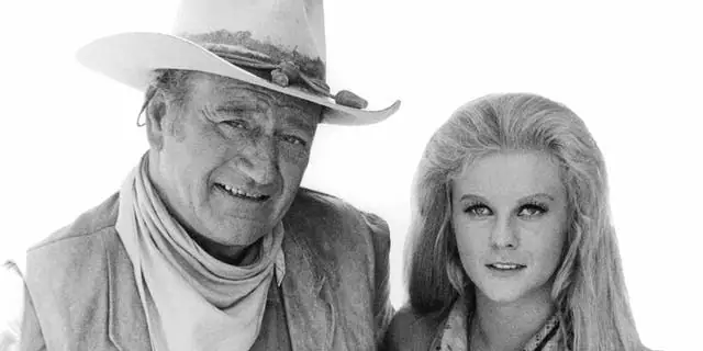 John Wayne holding Ann-Margret in publicity portrait for the film 'The Train Robbers', 1973.