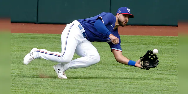 Texas Rangers center fielder Joey Gallo makes a diving catch against the Milwaukee Brewers during the third inning of a preseason baseball game Tuesday, March 30, 2021, in Arlington, Texas. (AP Photo/Michael Ainsworth)
