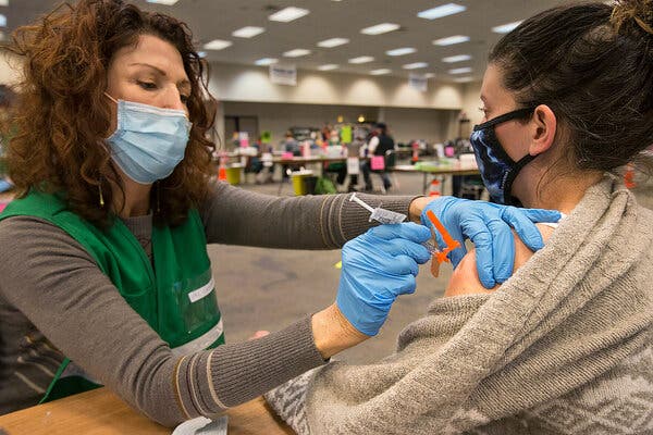 A teacher receiving a vaccine in January in Redmond, Ore. On Tuesday, Gov. Kate Brown of Oregon joined a handful of other states in setting a vaccination benchmark for lifting restrictions.