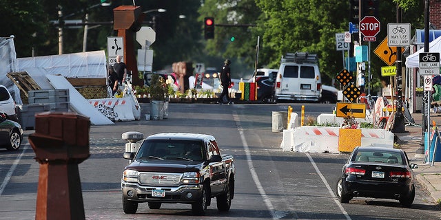 A vehicle travels along Chicago Ave. S. near East 38th Street at George Floyd Square, Tuesday, June 8, 2021, in Minneapolis, after city crews returned to remove debris and barriers for the second time in an attempt to open the intersection to traffic. (David Joles/Star Tribune via AP)