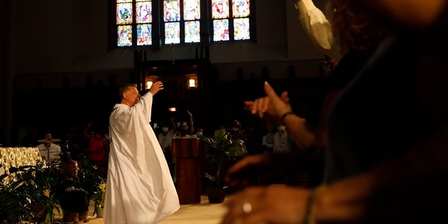 Parishioners raise their hands as Rev. Michael Pfleger conducts his first Sunday church service as a senior pastor at St. Sabina Catholic Church following his reinstatement by Archdiocese of Chicago after decades-old sexual abuse allegations against minors, Sunday, June 6, 2021, in the Auburn Gresham neighborhood in Chicago. (AP Photo/Shafkat Anowar)