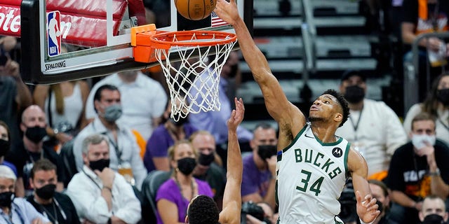 Phoenix Suns guard Devin Booker (1) scores as Milwaukee Bucks forward Giannis Antetokounmpo (34) is called for goaltending during the first half of Game 1 of basketball's NBA Finals, Tuesday, July 6, 2021, in Phoenix. (AP Photo/Ross D. Franklin)