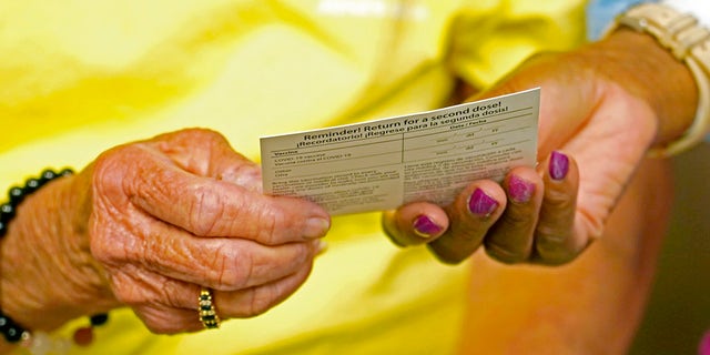 A woman receives a vaccination card after receiving a shot of the Johnson &amp; Johnson COVID-19 vaccine. (AP Photo/Rogelio V. Solis)