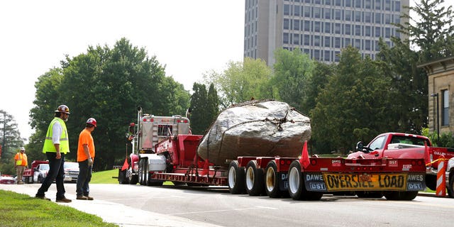 A flatbed trailer pull away from Observatory Hill with Chamberlin Rock in tow in Madison, Wis., Friday, Aug. 6, 2021.  The University of Wisconsin is removing the 70-ton boulder from its Madison campus at the request of minority students who view the rock as a symbol of racism. Chamberlin Rock, on the top of Observatory Hill, is named after Thomas Crowder Chamberlin, a geologist and former university president.     (Kayla Wolf/Wisconsin State Journal via AP)