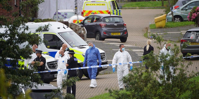 Forensic officers walk in Biddick Drive in the Keyham area of Plymouth, England on Friday, where six people were killed in a shooting incident.