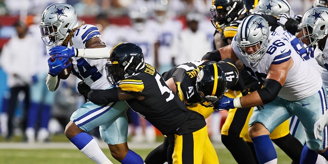 Dallas Cowboys running back Rico Dowdle (34) tries to escape the grasp of Pittsburgh Steelers linebacker Ulysees Gilbert III during the first half of the Pro Football Hall of Fame NFL preseason game Thursday, Aug. 5, 2021, in Canton, Ohio. (Associated Press)