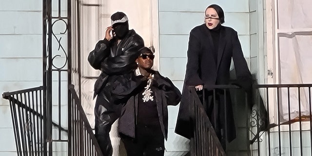 From left, a masked Kanye West, DaBaby and Marilyn Manson hang out on the stoop of a replica of the house of West's late mother Donda, at Soldier Field in Chicago, Aug. 26, 2021. (Brian Prahl/MEGA)