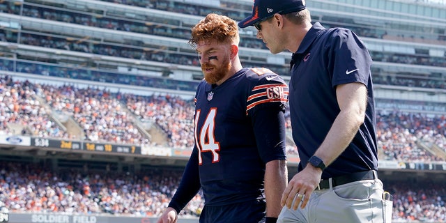 Chicago Bears quarterback Andy Dalton walks to the locker room with a trainer during the first half of an NFL football game against the Cincinnati Bengals Sunday, Sept. 19, 2021, in Chicago.
