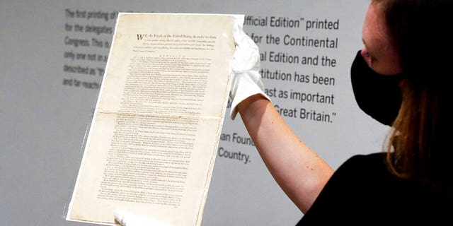 Ella Hall, a specialist in Books and Manuscripts at Sotheby's, in New York, holds a 1787 printed copy of the U.S. Constitution. (AP Photo/Richard Drew)