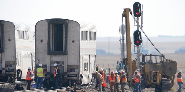 Workers examine a train car, Monday, Sept. 27, 2021, from an Amtrak train that derailed Saturday, near Joplin, Mont. 