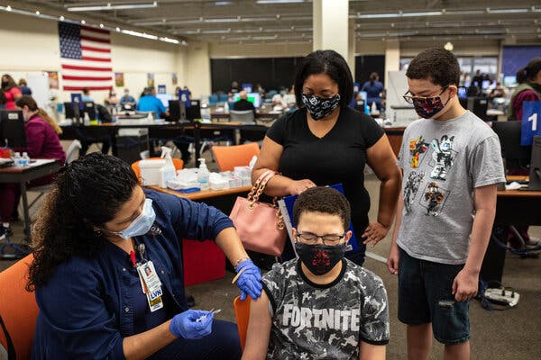 Damarcus Crimes, 13, receiving a dose of the Pfizer-BioNTech vaccine while his mother, Christina, and brother, Deshaun, 13, look on in San Antonio, Texas, in May.