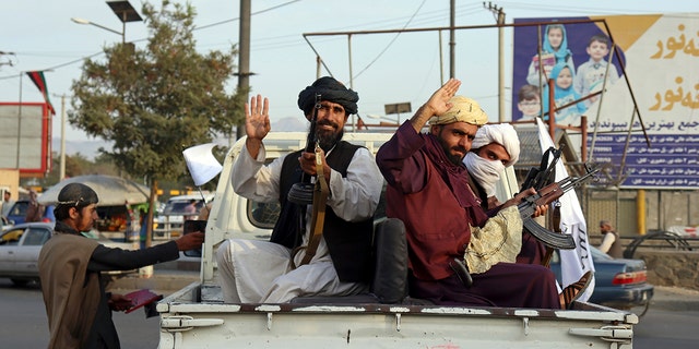 Taliban fighters wave from the back of a pickup truck, in Kabul, Afghanistan, Monday, Aug. 30, 2021. (AP Photo/Khwaja Tawfiq Sediqi)