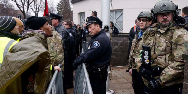 Nov. 18, 2015: A Black Lives Matter supporter, left, talks to Minneapolis police guarding the Fourth Precinct entrance in Minneapolis.