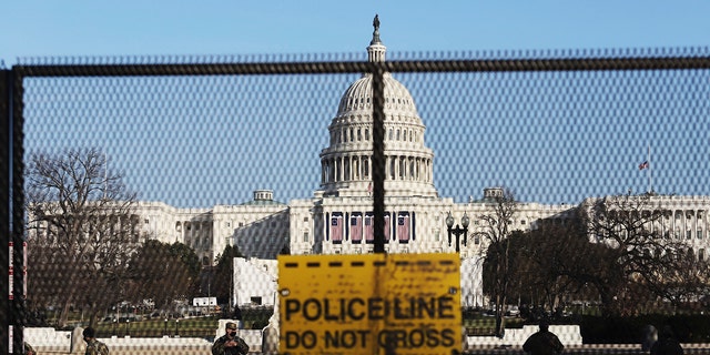 National guards are seen Wednesday, Jan. 13, 2021, on a fence that was erected to reinforce security at the Capitol in Washington. 