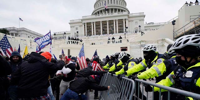 In this Wednesday, Jan. 6, 2021 file photo, Trump supporters try to break through a police barrier at the Capitol in Washington.  Right-wing extremism has previously mostly played out in isolated pockets of America or in smaller cities. In contrast, the deadly attack by rioters on the U.S. Capitol targeted the very heart of government. It brought together members of disparate groups, creating the opportunity for extremists to establish links with each other. (AP Photo/Julio Cortez, File)