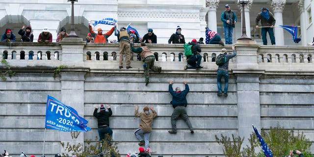 In this Wednesday, Jan. 6, 2021 file photo, supporters of President Donald Trump climb the west wall of the the U.S. Capitol in Washington. In what could be the longest of legal longshots, several of those arrested for storming the U.S. Capitol are holding out hope that President Donald Trump will use some of his last hours in office to grant all the rioters a full and complete pardon. (AP Photo/Jose Luis Magana)