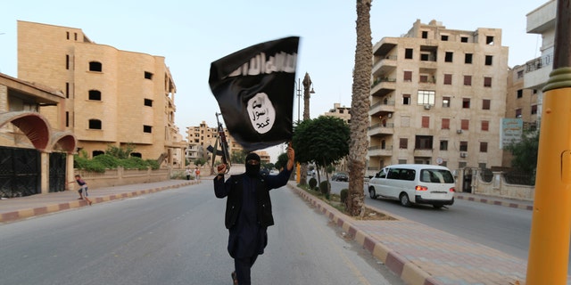 A ISIS member waves the radical group's flag. 