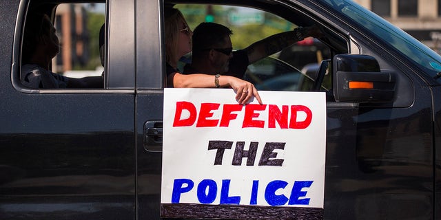 A woman holds a sign in Bloomington, Indiana, that says "Defend the Police." (Photo by Jeremy Hogan/SOPA Images/LightRocket via Getty Images)