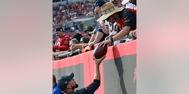 A Tampa Bay Buccaneers fan gives quarterback Tom Brady's 600th career touchdown pass back after wide receiver Mike Evans threw the ball to the fan during the first half of an NFL football game against the Chicago Bears Sunday, Oct. 24, 2021, in Tampa, Fla.