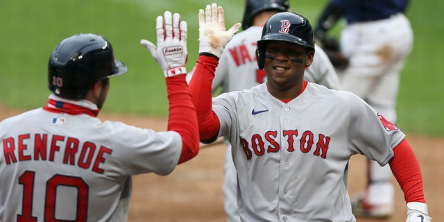 Boston Red Sox Rafael Devers (11) high fives teammate Boston Red Sox Hunter Renfroe (10) after hitting a home run against the Minnesota Twins during the ninth inning of a baseball game, Tuesday, April 13, 2021, in Minneapolis. Boston won 4-2.
