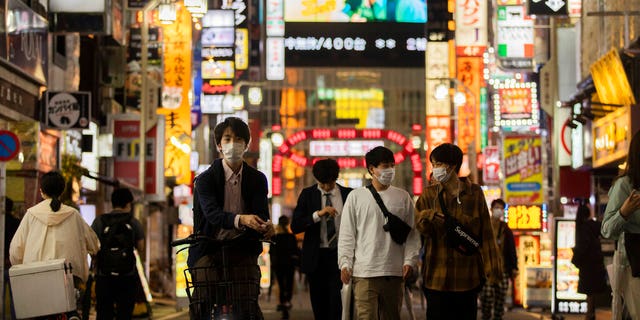 FILE - In this Oct. 1, 2021, file photo, people walk through the famed Kabukicho entertainment district of Tokyo on the first night of the government's lifting of a coronavirus state of emergency. Almost overnight, Japan has become a stunning, and somewhat mysterious, coronavirus success story. Case numbers are way down, but experts worry that without knowing how exactly it cut cases so drastically, the nation may be in store for another devastating wave like during the summer. (AP Photo/Hiro Komae, File)
