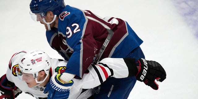 Colorado Avalanche left wing Gabriel Landeskog, top, holds Chicago Blackhawks left wing Dominik Kubalik and is called for a penalty during the second period of an NHL hockey game Wednesday, Oct. 13, 2021, in Denver.