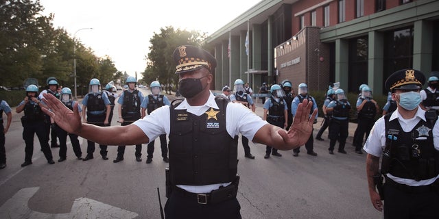 A Chicago police officer attempts to deescalate tension as Englewood residents clash with demonstrators protesting outside the 7th District station of the Chicago Police Department on August 11, 2020 in Chicago, Illinois. (Photo by Scott Olson/Getty Images)