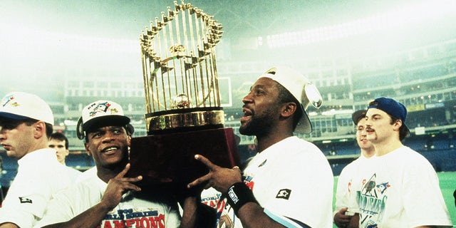 TORONTO, ON - OCTOBER 23:  Rickey Henderson (L) and Joe Carter of the Toronto Blue Jays carry the World Series trophy after the Blue Jays victory during World Series game six between the Philadelphia Phillies and Toronto Blue Jays on October 23, 1993 at the Skydome in Toronto, Ontario, Canada. The Blue Jays defeated the Phillies 8-6.