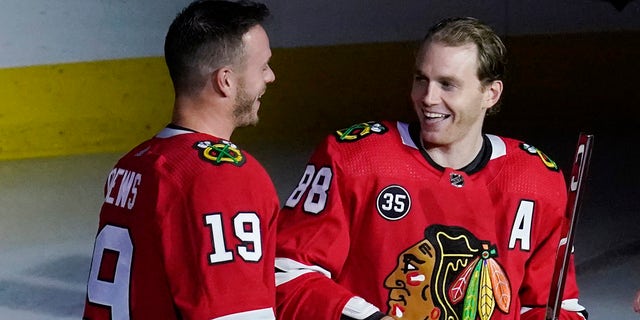 Chicago Blackhawks right wing Patrick Kane, right, smiles as he is joined by center Jonathan Toews while being honored for his 1,000th career NHL hockey game, which happened in March, before the team's game against the Vancouver Canucks in Chicago, Thursday, Oct. 21, 2021. 