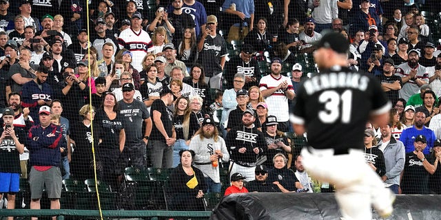 FILE - In this Saturday, Oct. 2, 2021, file photo, fans stand as they watch Chicago White Sox relief pitcher Liam Hendriks work during the ninth inning of a baseball game against the Detroit Tigers in Chicago.