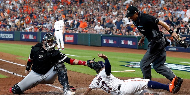 Jose Altuve of the Houston Astros slides safely past the tag of Yasmani Grandal of the Chicago White Sox to score during the third inning of Game 1 of the American League Division Series at Minute Maid Park on Oct. 7, 2021 in Houston, Texas.