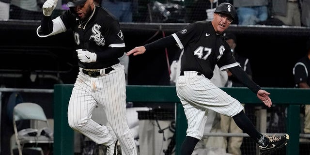 Chicago White Sox's Yoan Moncada, left, celebrates with third base coach Joe McEwing after hitting a two-run home run during the eighth inning of a baseball game against the Detroit Tigers in Chicago, Saturday, Oct. 2, 2021.